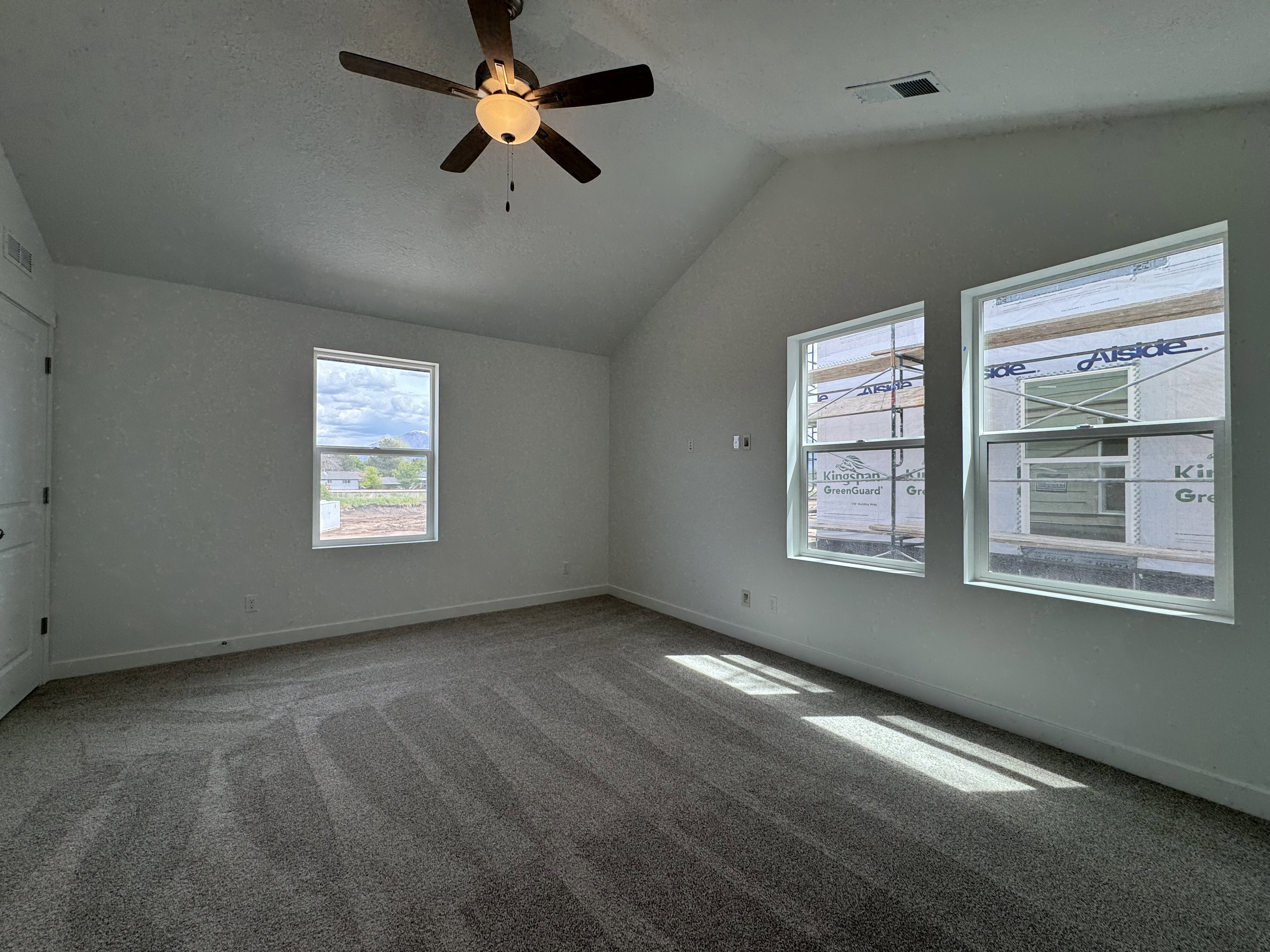 Carpeted empty room with lofted ceiling and a ceiling fan