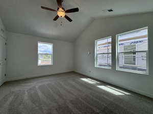 Carpeted empty room with lofted ceiling and a ceiling fan