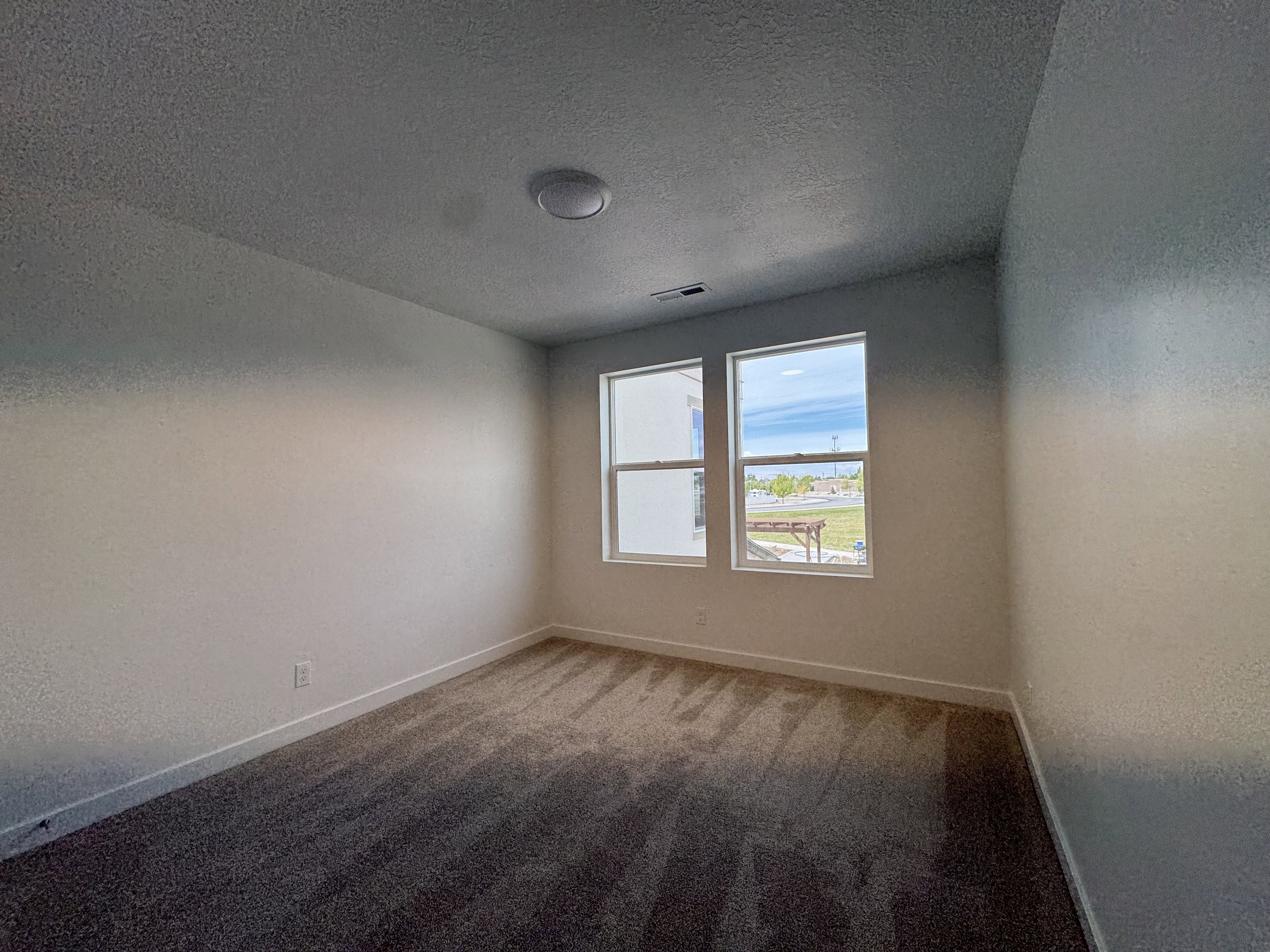 Carpeted spare room with a textured ceiling and a textured wall