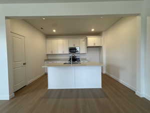 Kitchen with white cabinetry, dark wood-type flooring, recessed lighting, a kitchen island with sink, and stainless steel appliances