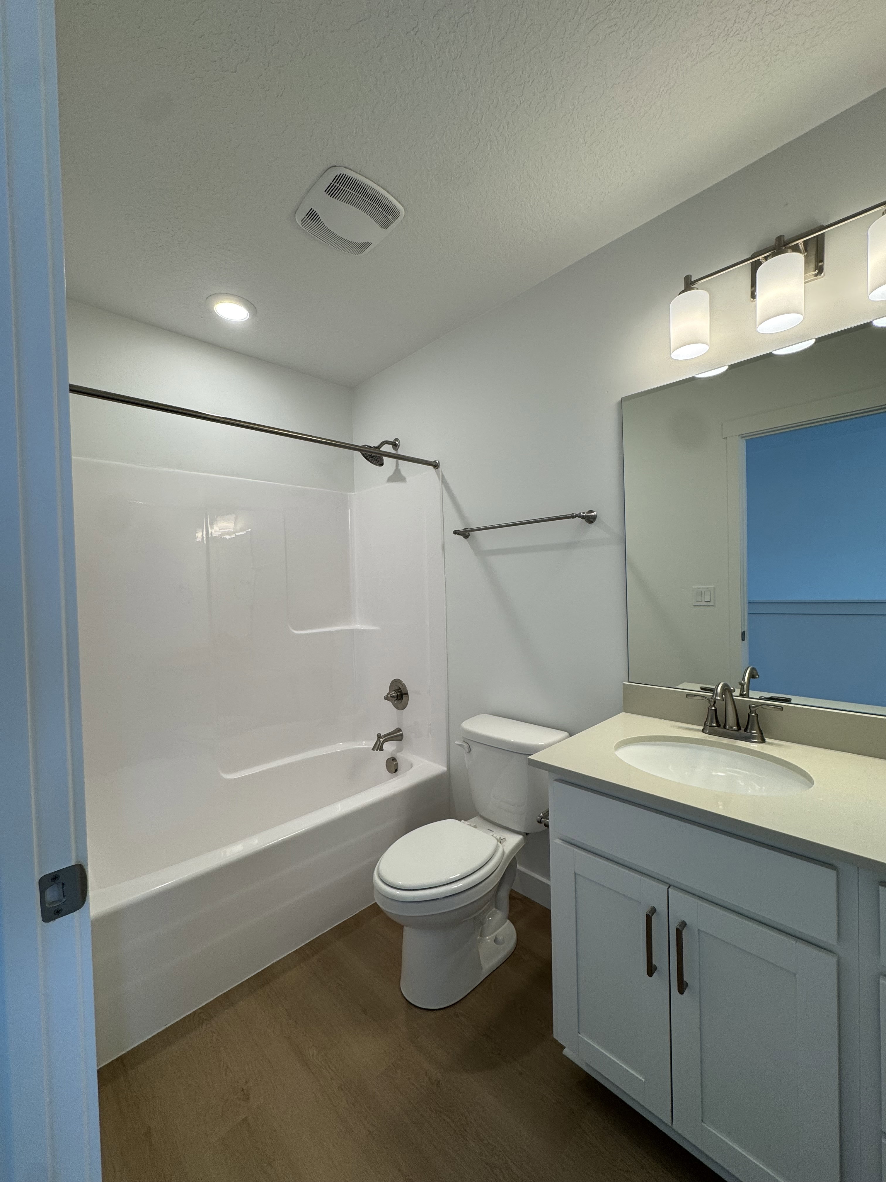 Bathroom with vanity, dark wood-type flooring, shower / bath combination, and a textured ceiling