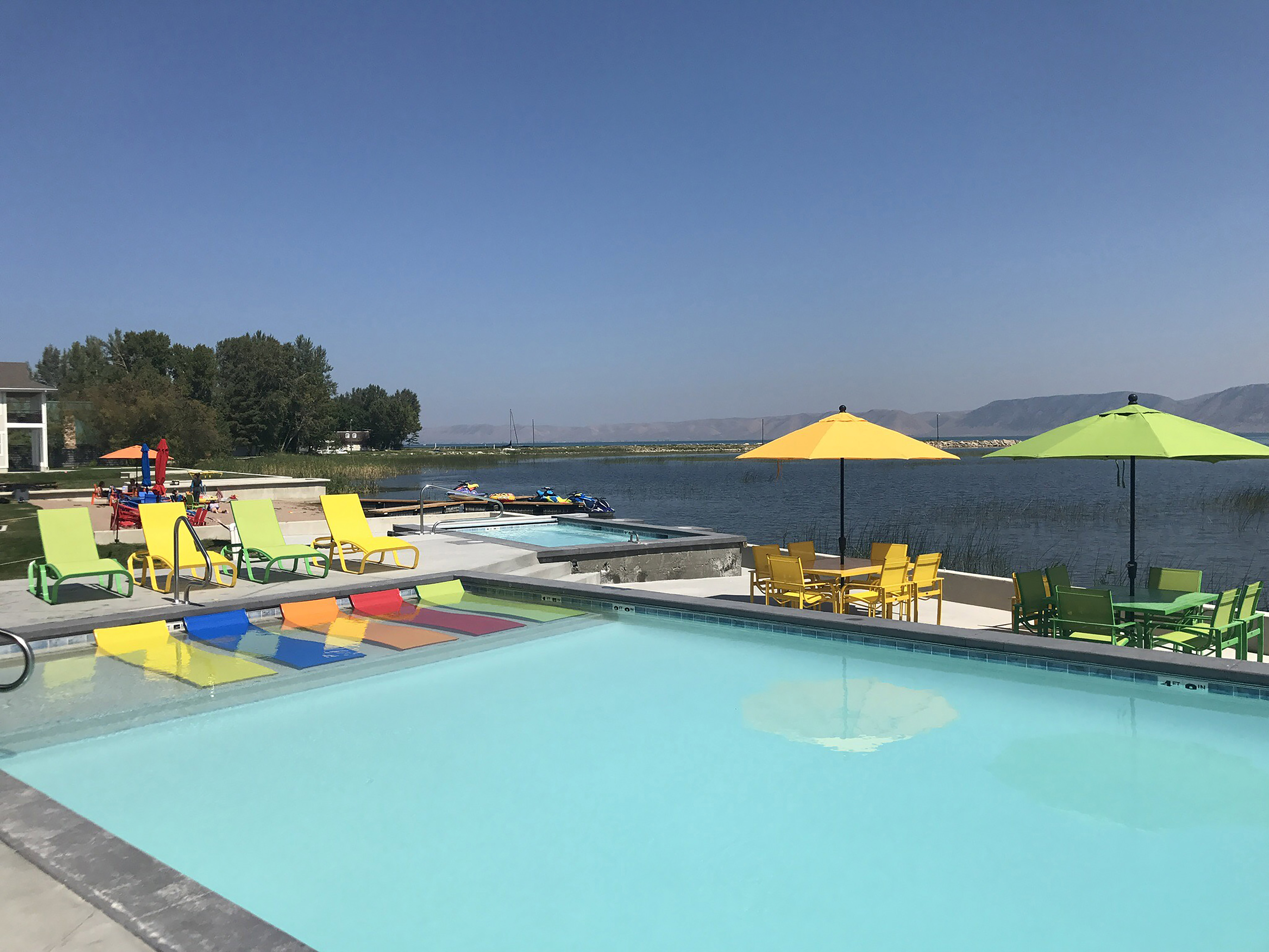 Community pool with outdoor dining space, a water view, and a jacuzzi
