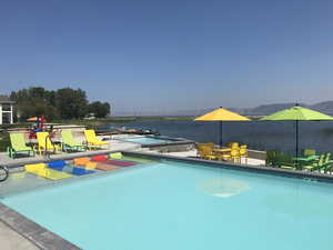 Community pool with outdoor dining space, a water view, and a jacuzzi