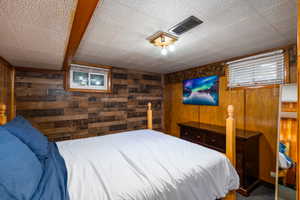 Bedroom with wood walls and dark colored carpet