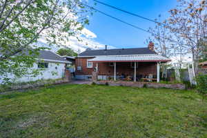 Back of property featuring a patio area, a chimney, and brick siding