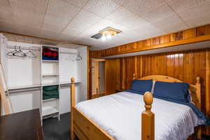 Bedroom featuring a closet, dark carpet, and wooden walls