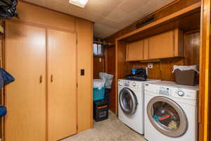 Laundry area featuring cabinet space, wood walls, washer and dryer, and light carpet