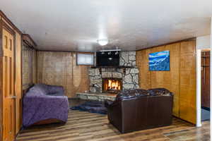 Living area with a stone fireplace, dark wood-style flooring, and a textured ceiling