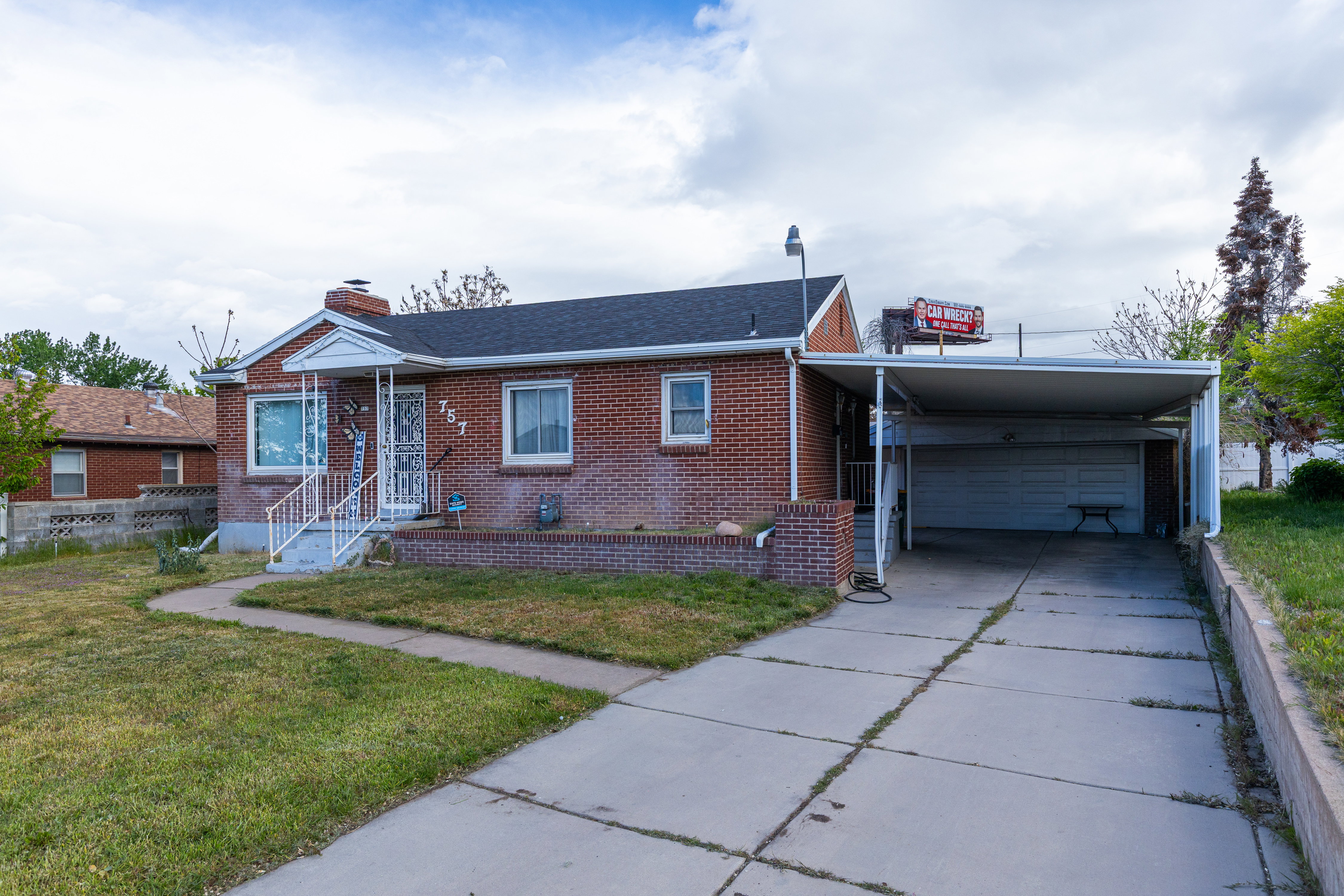 View of front of home with concrete driveway, a garage, brick siding, a chimney, and a carport