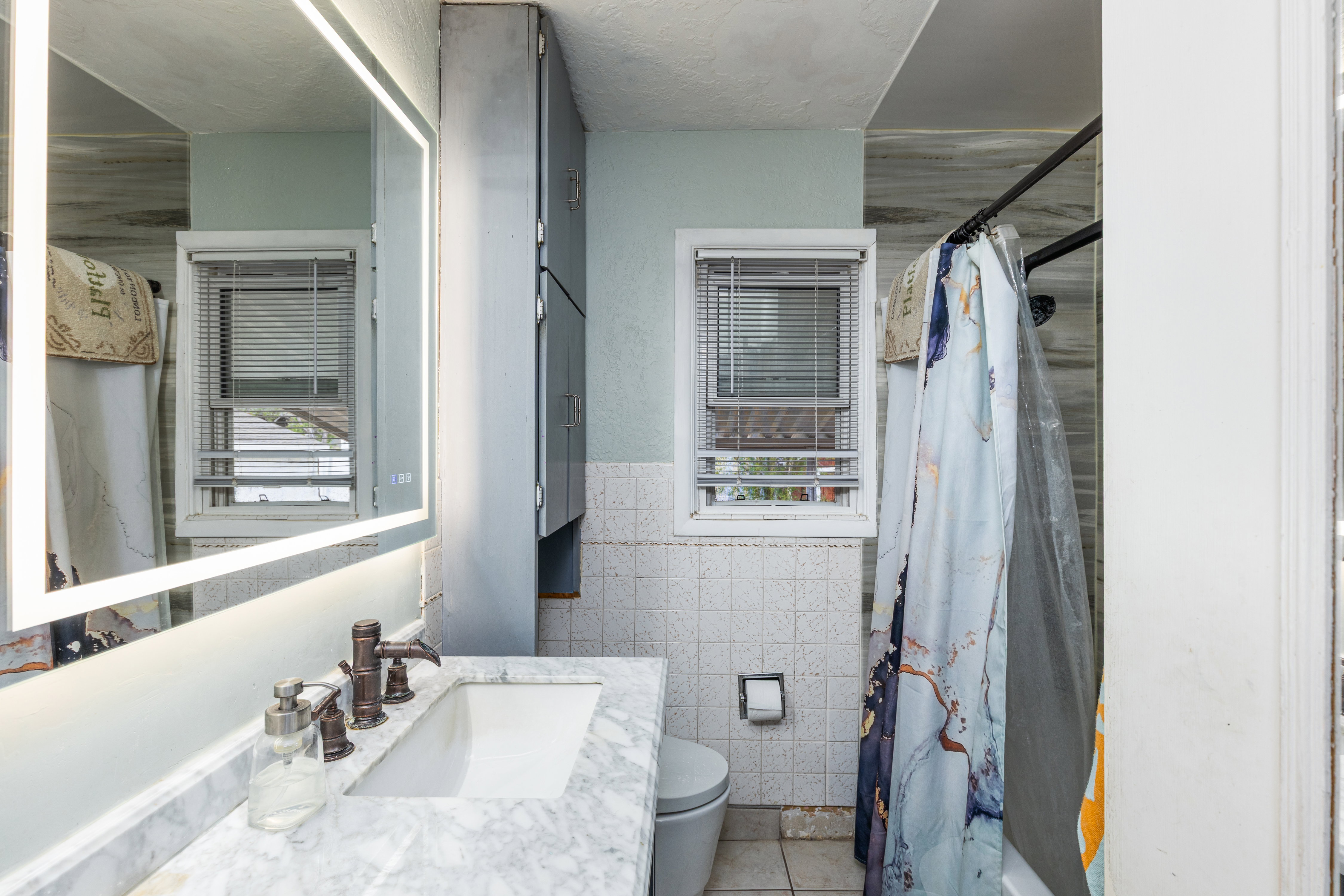 Bathroom featuring vanity, tile walls, wainscoting, plenty of natural light, and light tile patterned floors