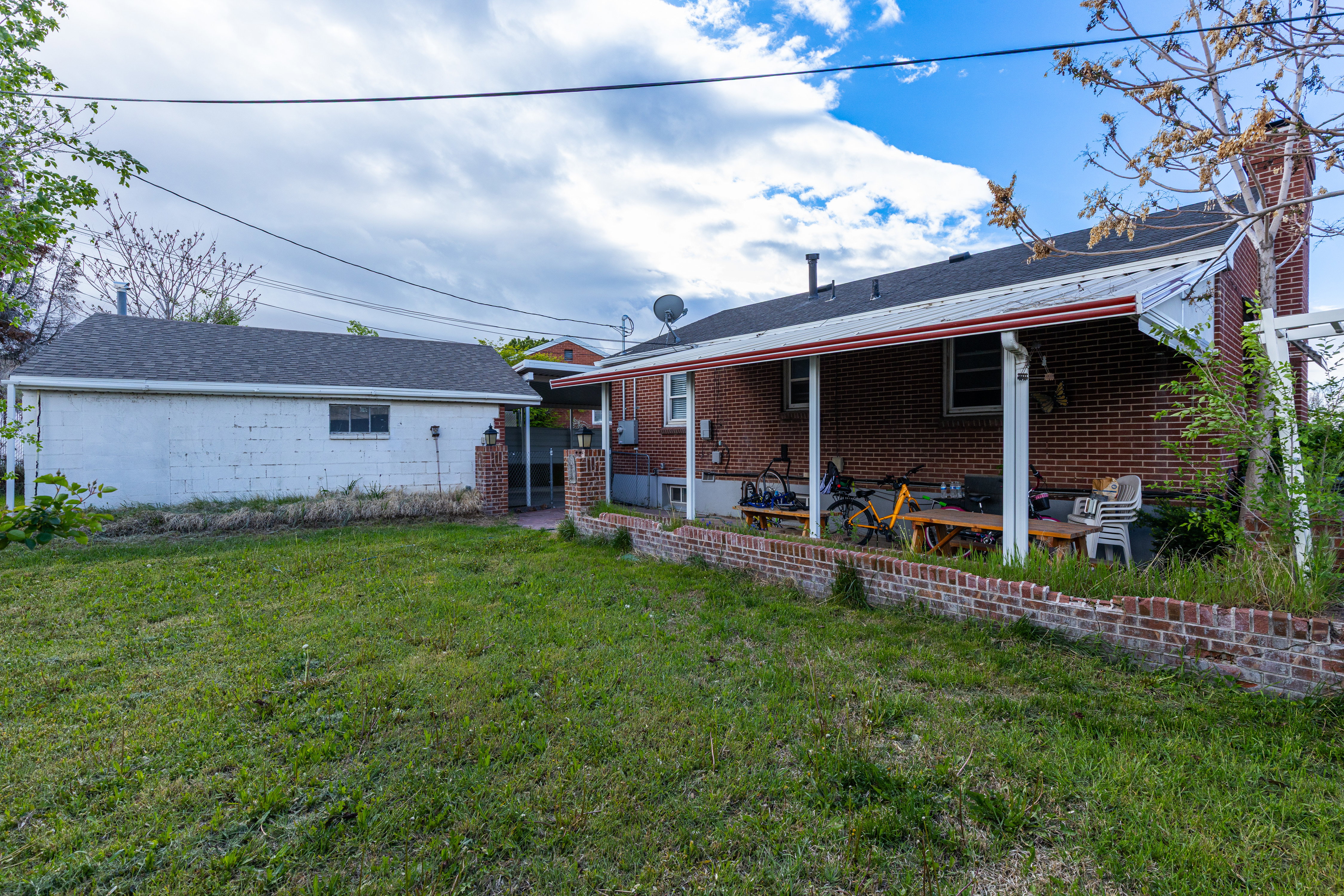 Back of house featuring a lawn, a patio, brick siding, and a chimney