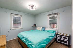 Bedroom featuring dark colored carpet and a textured ceiling