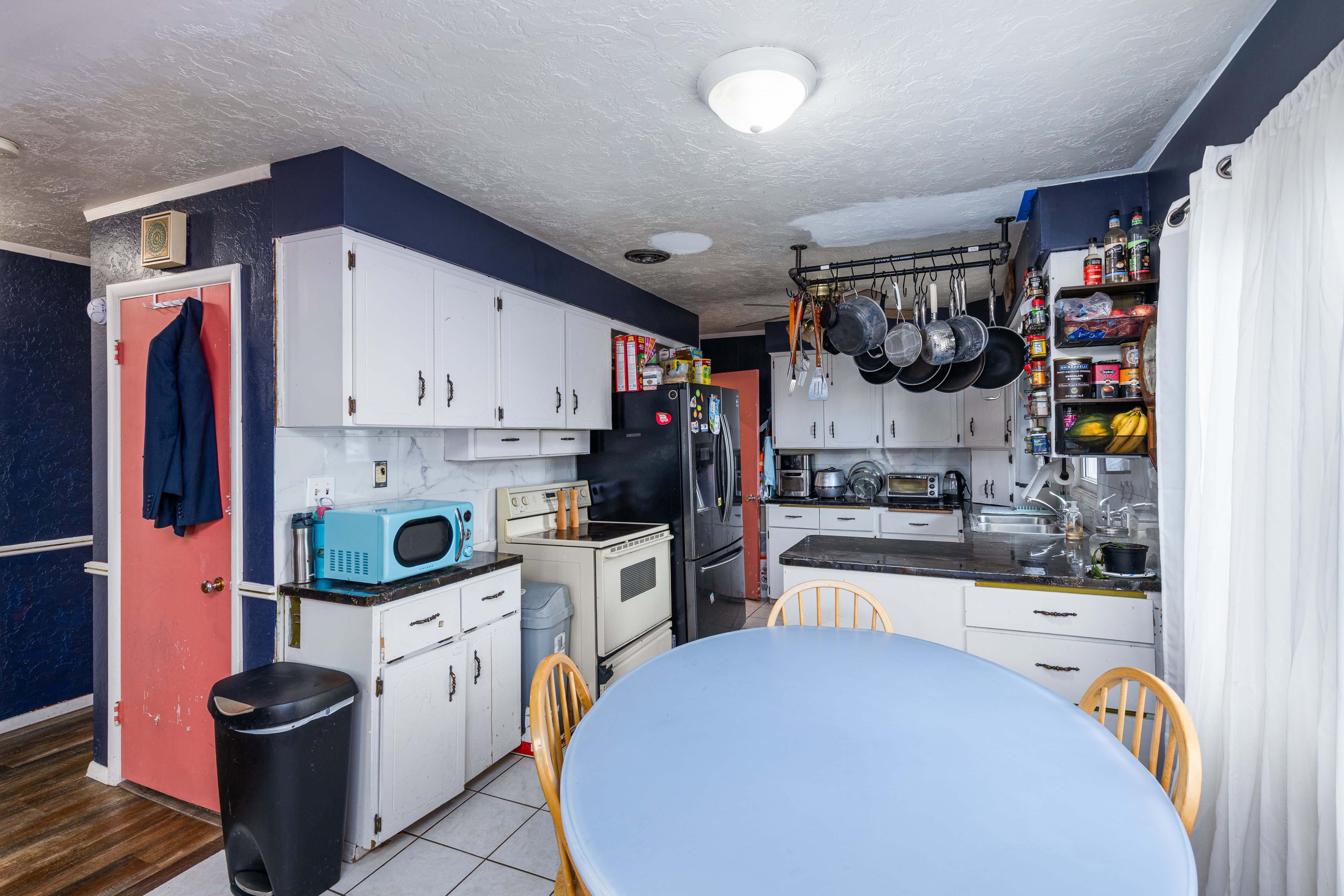 Kitchen featuring dark countertops, white cabinetry, white range with electric cooktop, a textured ceiling, and a textured wall