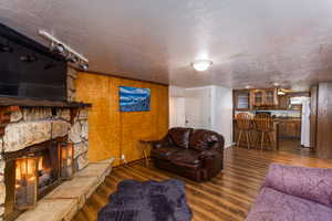 Living room with dark wood-type flooring, a fireplace, a textured ceiling, and bar area
