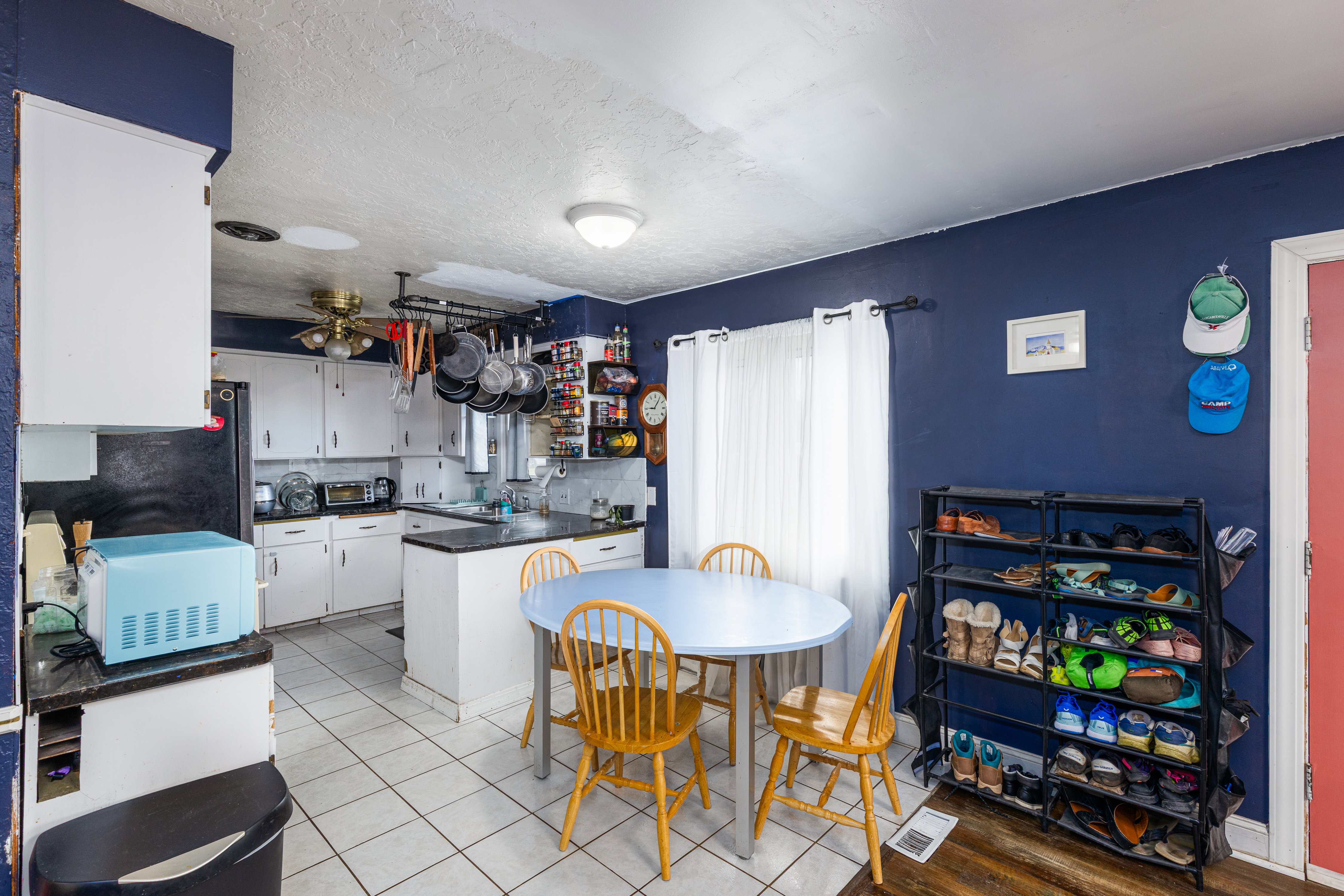 Kitchen featuring white cabinets, dark countertops, a peninsula, white microwave, and a ceiling fan