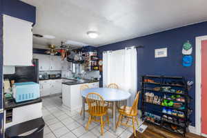 Kitchen featuring white cabinets, dark countertops, a peninsula, white microwave, and a ceiling fan