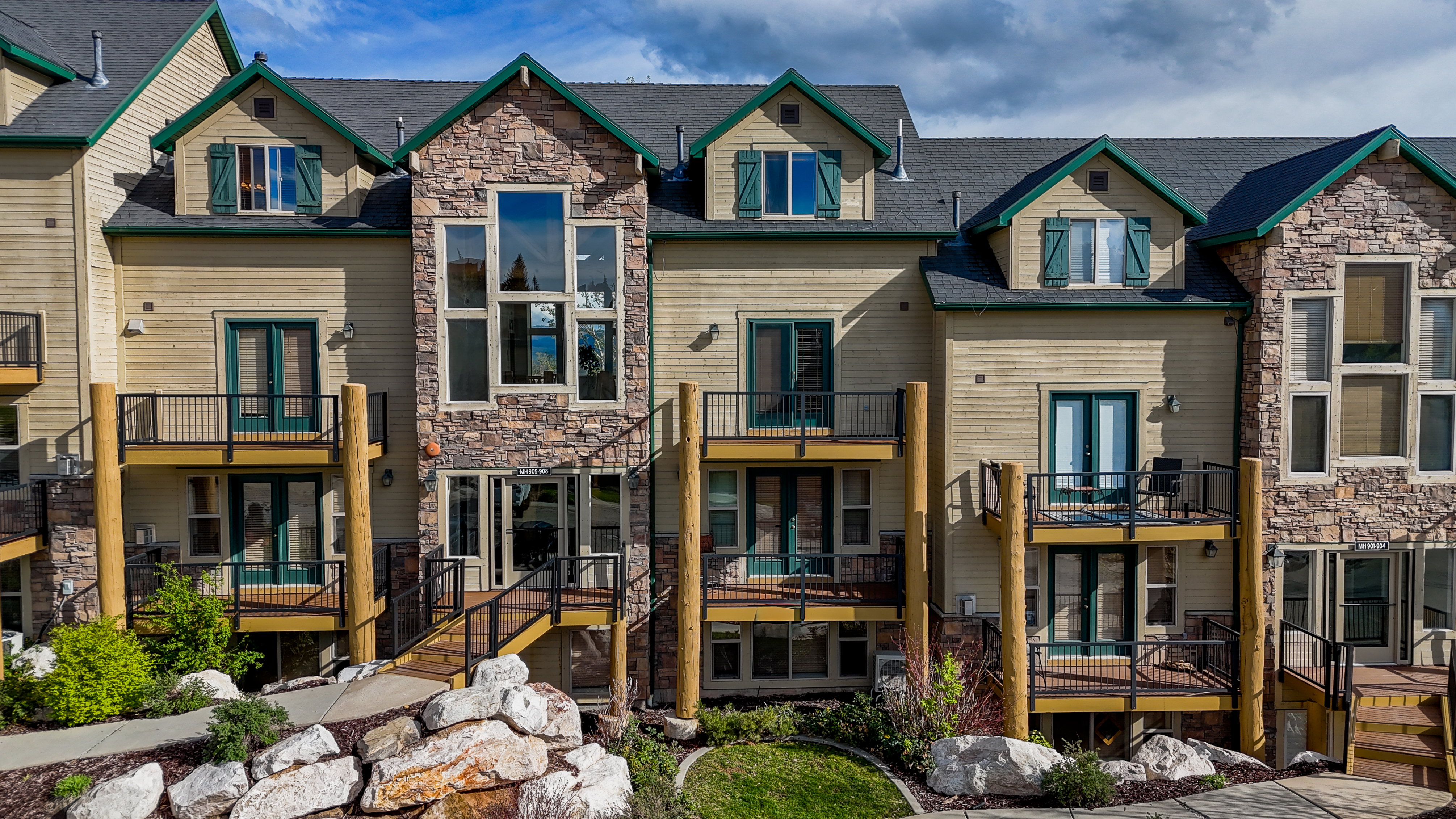Rear view of house with a balcony, french doors, stone siding, and a residential view