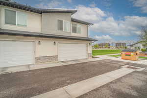 View of front of house featuring stucco siding, a residential view, an attached garage, and a front yard