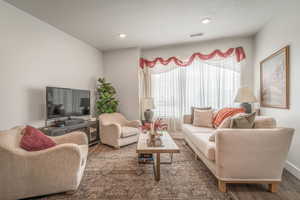 Living area featuring dark wood-type flooring and recessed lighting