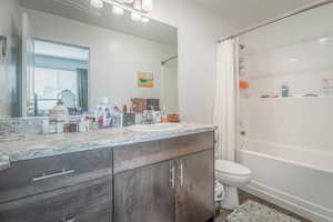 Bathroom featuring vanity, shower / bathtub combination with curtain, and dark wood-type flooring