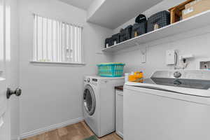 Laundry area with separate washer and dryer and light wood-style floors