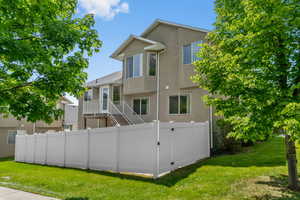Rear view of house with stucco siding, a gate, and a balcony