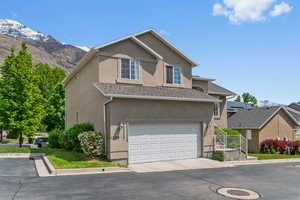 Traditional-style home featuring stucco siding, a mountain view, roof with shingles, and a garage