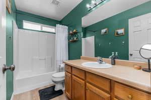 Bathroom with vanity, shower / bath combo, and light wood finished floors