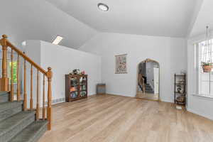 Interior space featuring healthy amount of natural light, vaulted ceiling, light wood finished floors, and arched walkways