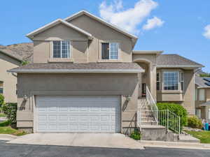 Traditional-style home featuring stucco siding, a garage, and driveway