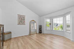 Unfurnished living room featuring light wood finished floors, lofted ceiling, and arched walkways