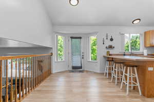 Kitchen with light wood-style floors, a kitchen breakfast bar, lofted ceiling, a peninsula, and wood finish cabinets