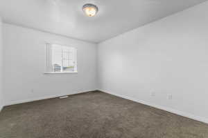 Unfurnished room featuring baseboards and dark colored carpet