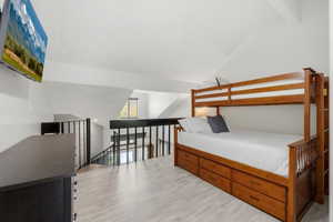 Bedroom with light wood-style flooring and lofted ceiling