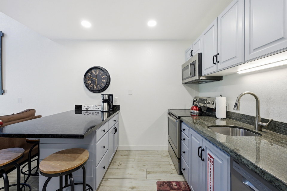 Kitchen with a peninsula, a breakfast bar area, dark stone counters, stainless steel appliances, and recessed lighting