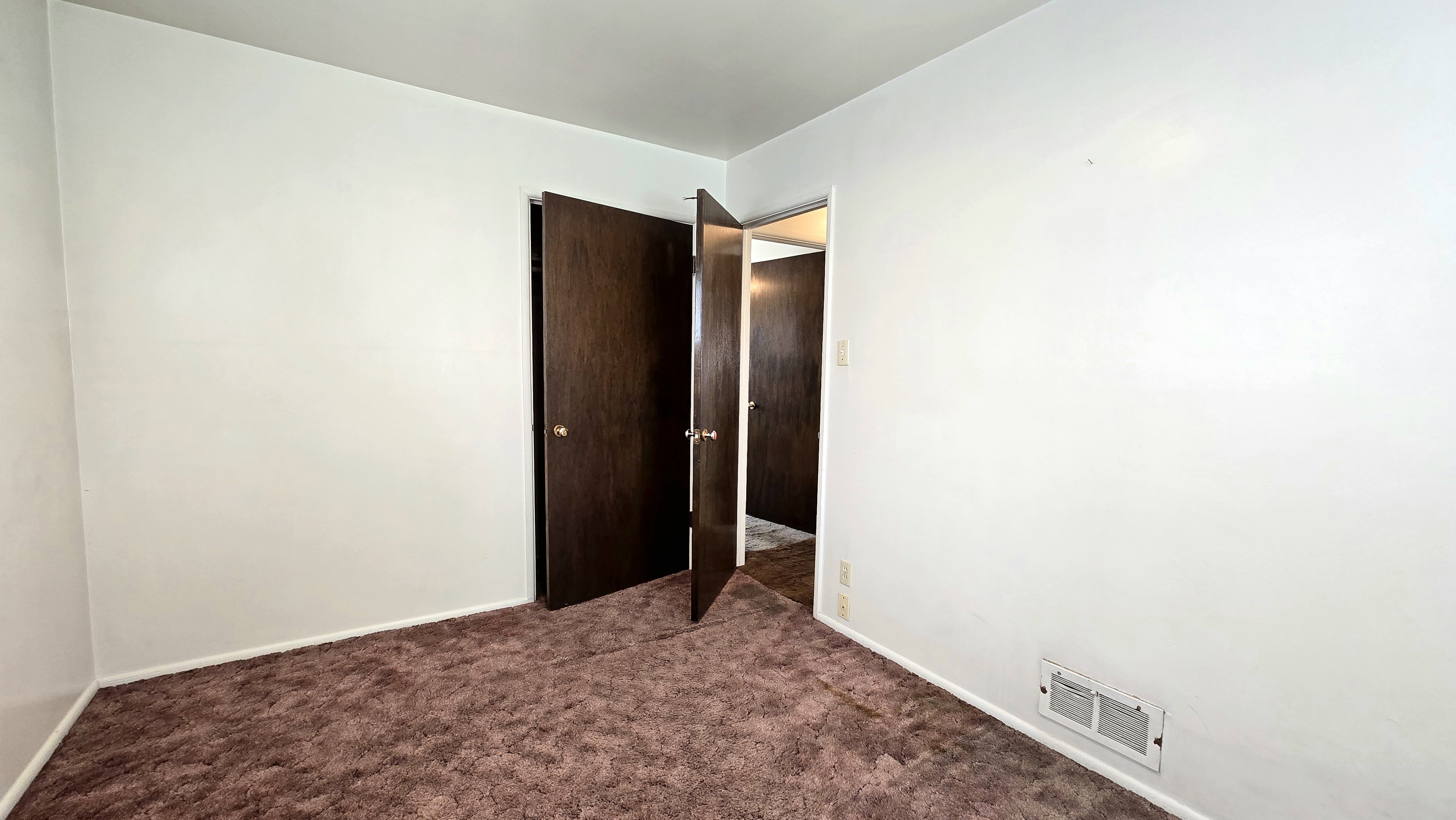 Spare room with dark colored carpet and baseboards