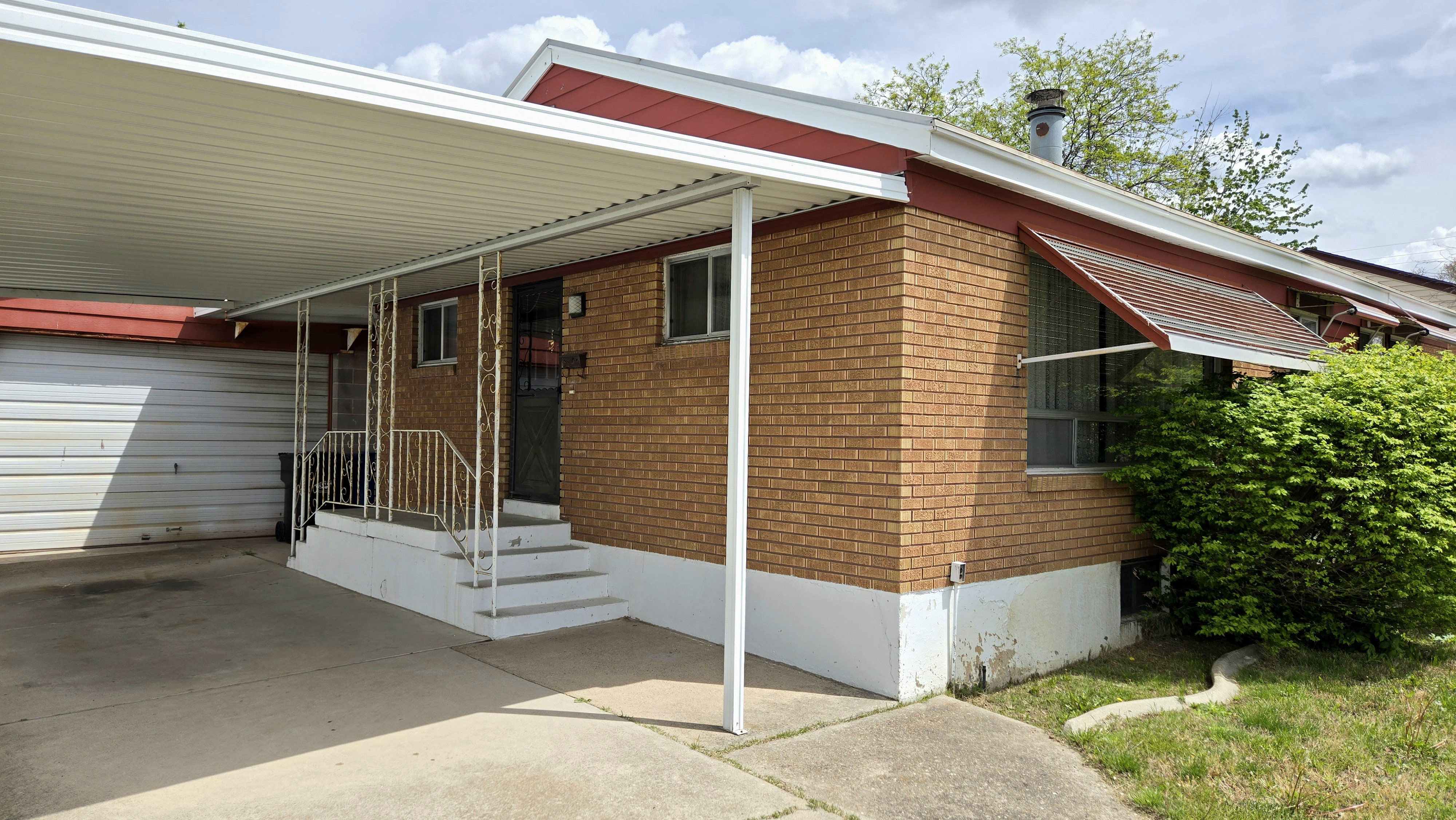 View of front of property with a carport and brick siding