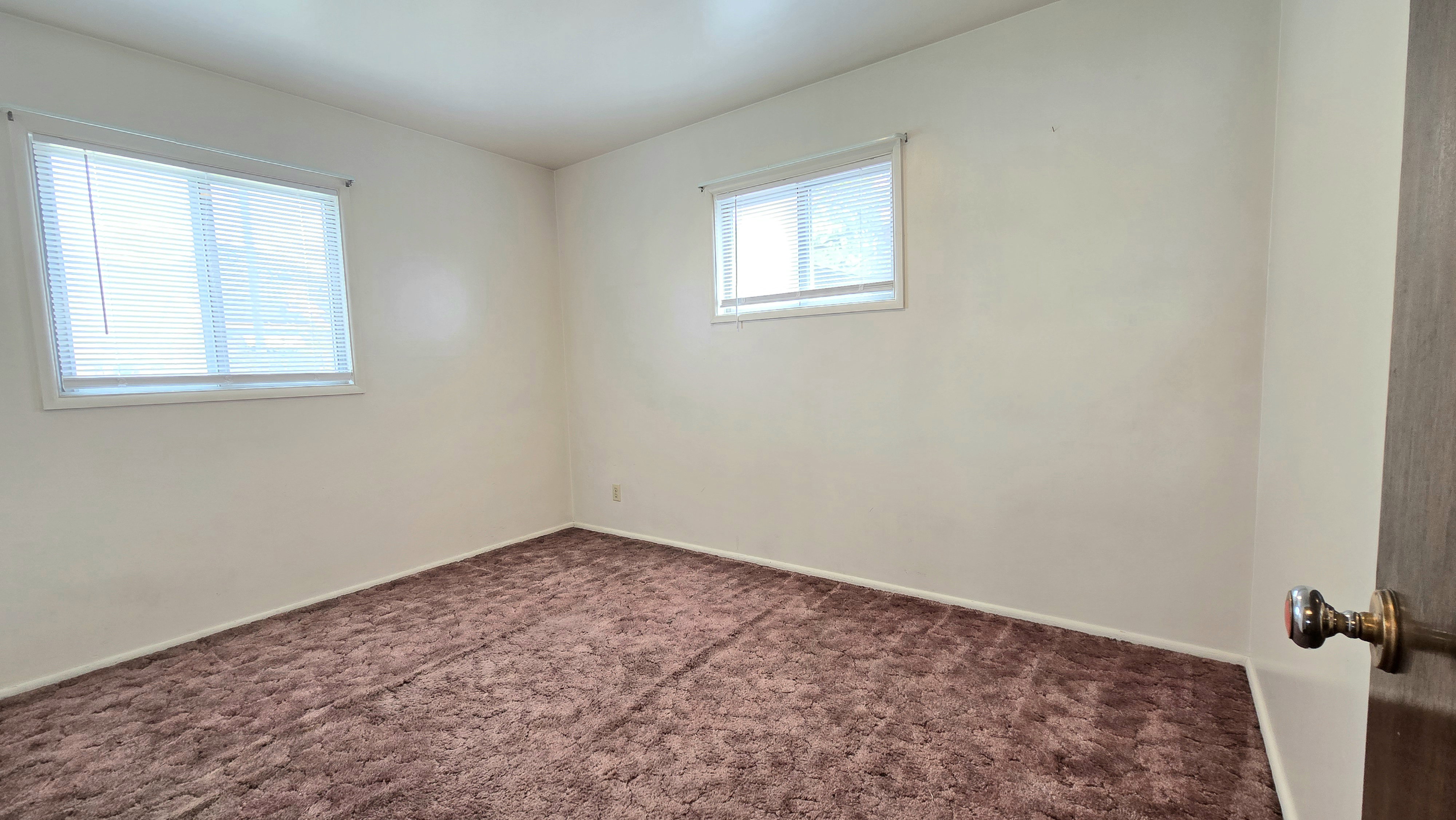 Spare room with dark carpet and baseboards