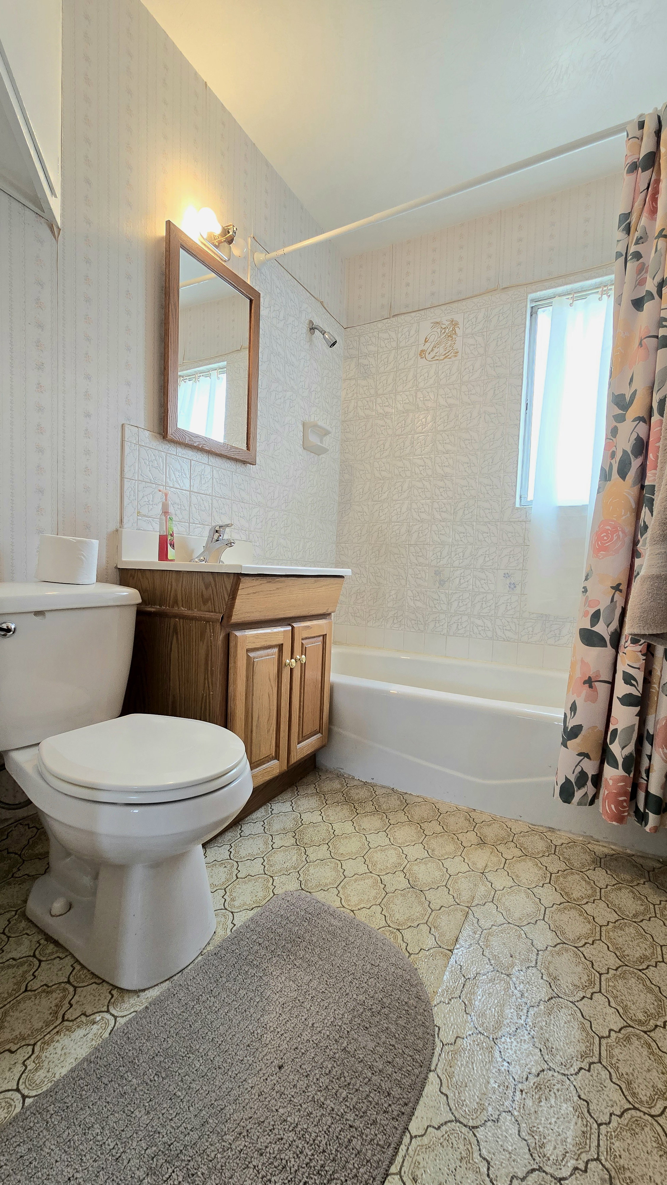 Full bath featuring shower / bath combo, vanity, and wallpapered walls