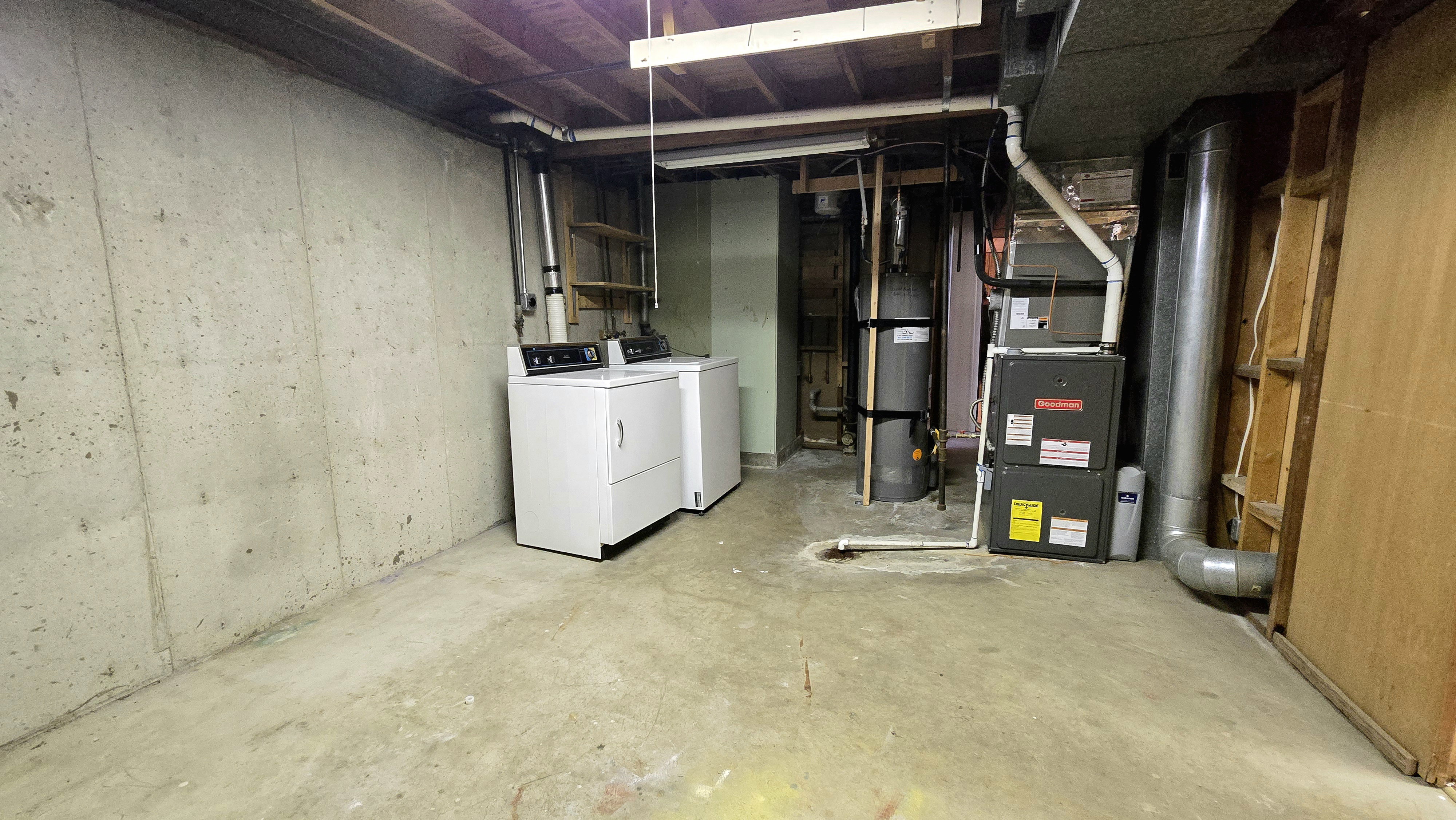 Unfinished basement featuring washer and clothes dryer, heating unit, and water heater