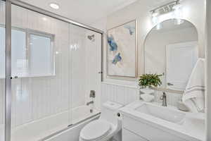 Bathroom with vanity, enclosed tub / shower combo, tile walls, and wainscoting