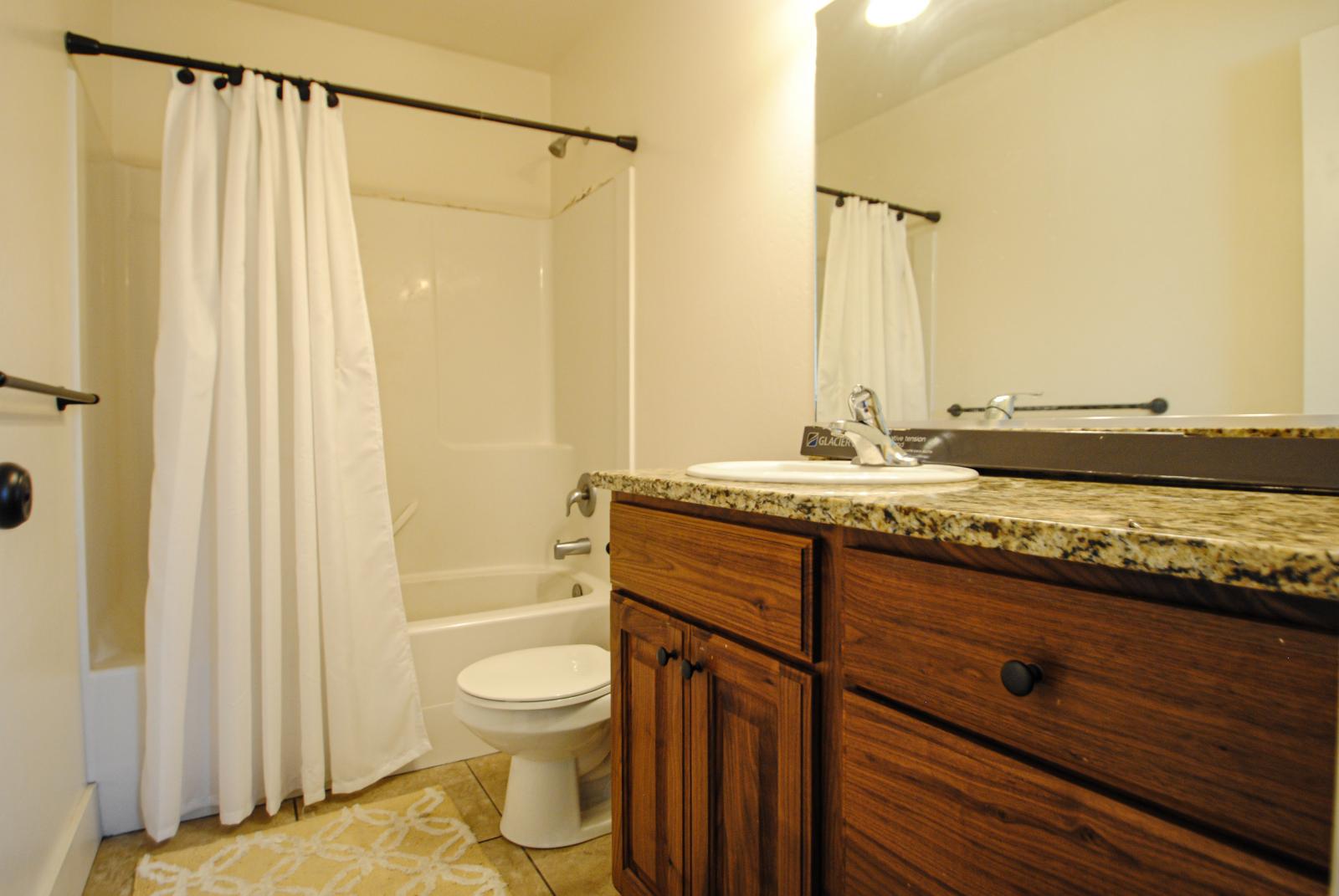 Full bath with vanity, shower / bath combo, and light tile patterned floors