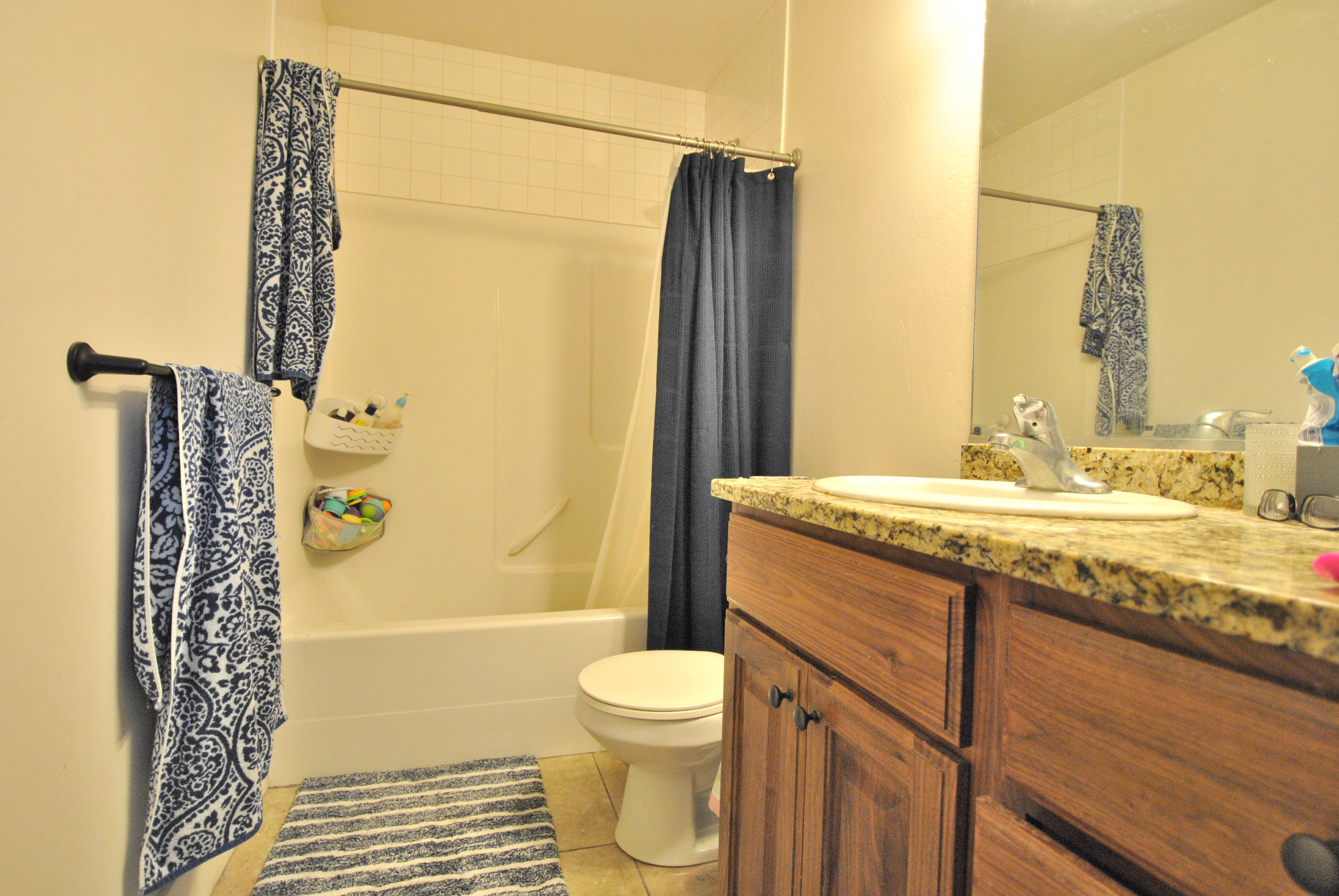 Full bathroom with vanity, shower / bathtub combination with curtain, and light tile patterned floors
