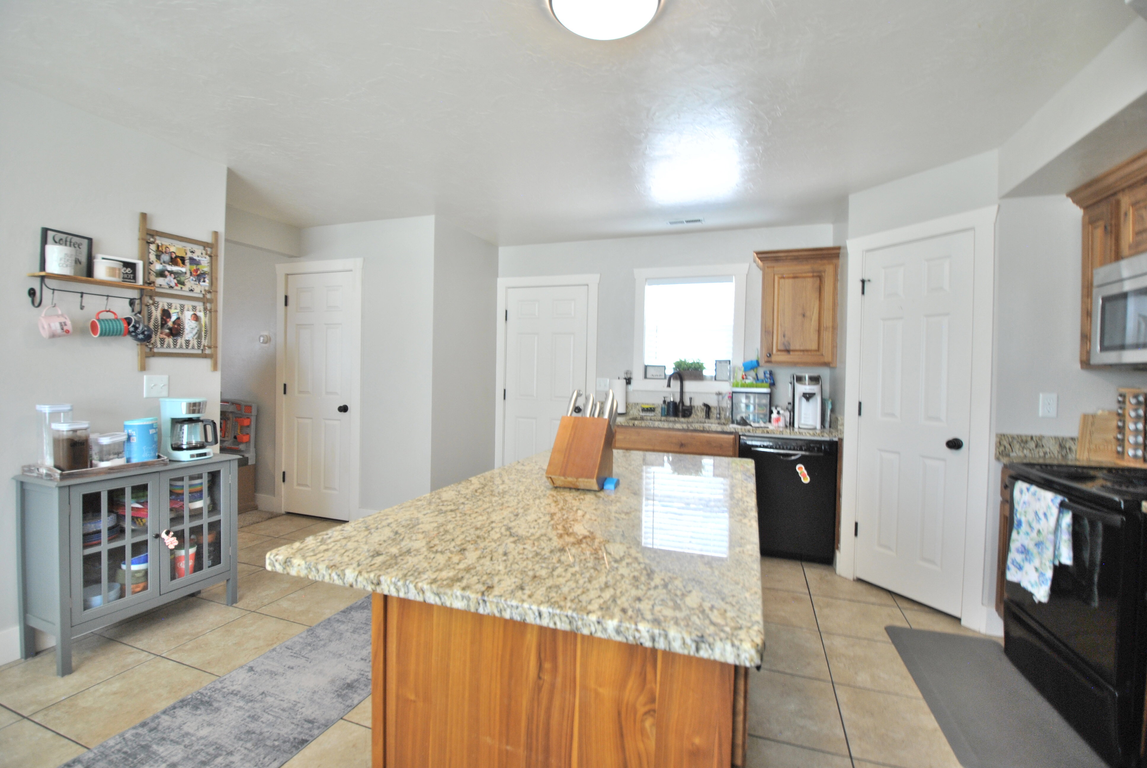 Kitchen with a center island, black appliances, light stone counters, and light tile patterned floors
