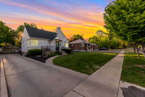 Bungalow-style home with a lawn, an outbuilding, a garage, a chimney, and a porch