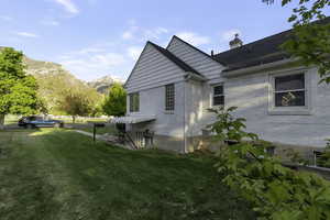 View of side of home with a yard, brick siding, a mountain view, and a chimney