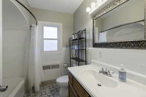 Bathroom featuring vanity, radiator heating unit, light tile patterned floors, and shower / tub combo