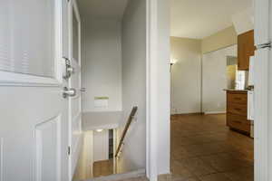 Hall with an upstairs landing and light tile patterned floors