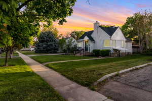 View of front of house with a yard, a chimney, and brick siding