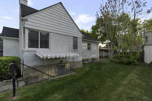 Rear view of house with a lawn, brick siding, a chimney, and roof with shingles